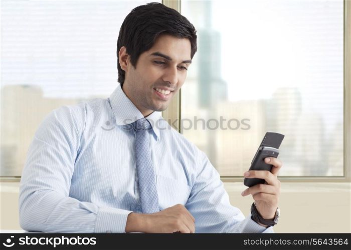 Happy young male executive reading text message