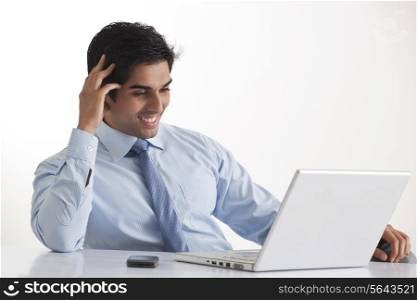 Happy young male executive smiling while looking at laptop