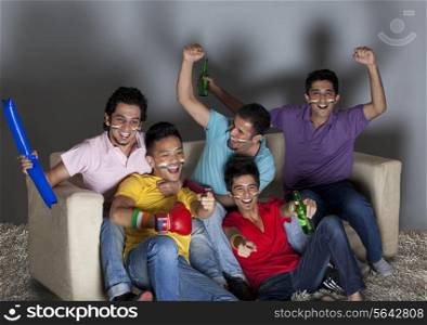 Happy young male friends enjoying a boxing match together at home