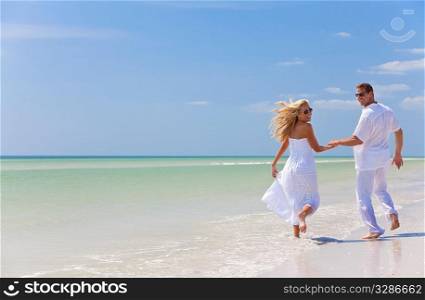 Happy young man and woman couple running, laughing and holding hands on a deserted tropical beach with bright clear blue sky