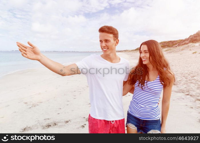 Happy young man and woman couple together walking on a beach. Happy senior man and woman couple together walking and pointing on a deserted beach