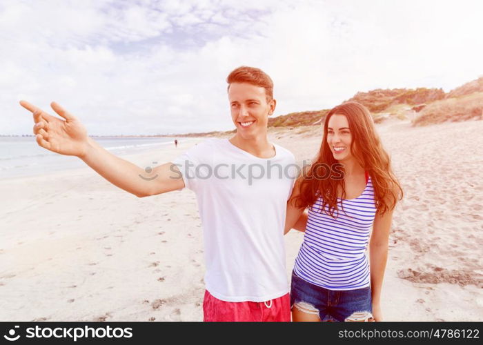 Happy young man and woman couple together walking on a beach. Happy senior man and woman couple together walking and pointing on a deserted beach