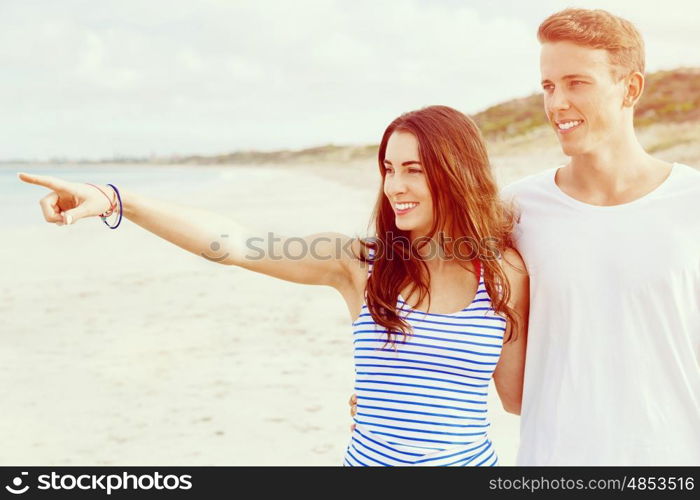 Happy young man and woman couple together walking on a beach. Happy senior man and woman couple together walking and pointing on a deserted beach