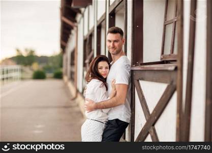 happy young man and woman having fun outdoors on a warm summer day. couple is hugging near horse rancho.. happy young man and woman having fun outdoors on a warm summer day. couple is hugging near horse rancho