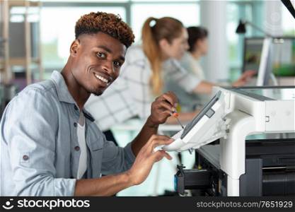 happy young man fixing a printer