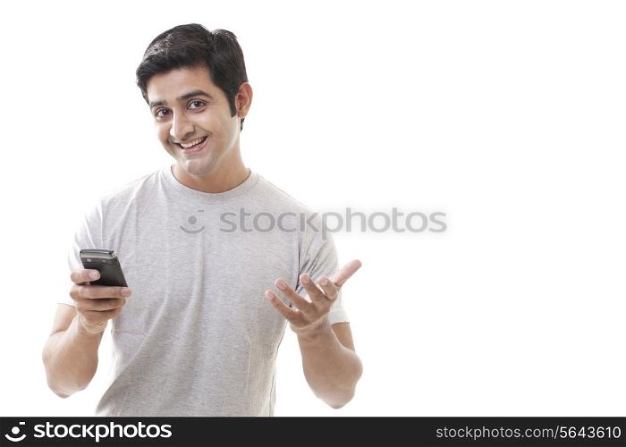 Happy young man gesturing while holding cell phone