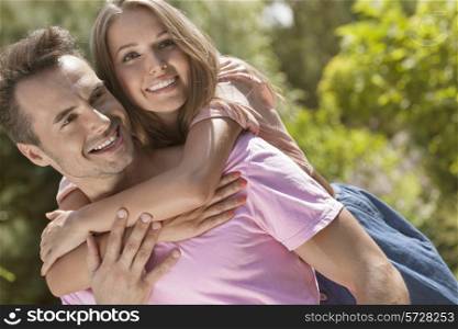 Happy young man giving piggyback ride to woman in park