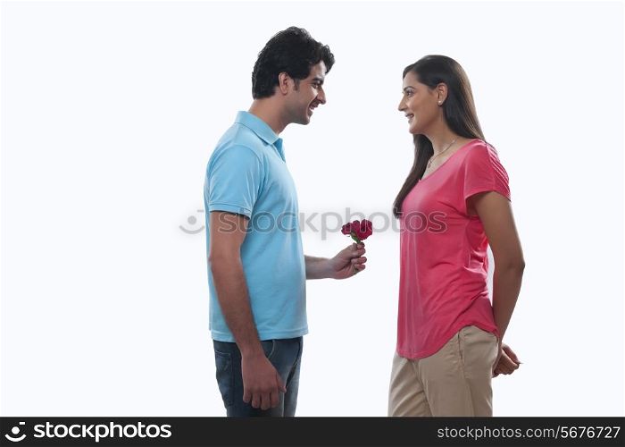 Happy young man giving rose to woman against white background