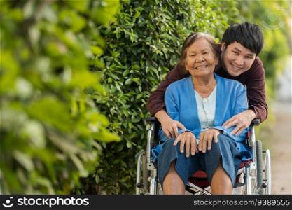 happy young man  grandson  embracing with senior woman in wheelchair at the park