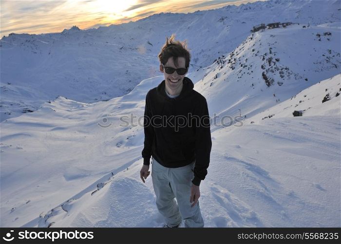 happy young man have fun at mountain peak on winter season with beautiful sunset