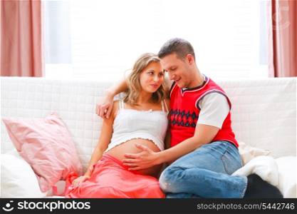 Happy young man holding his pregnant wifes belly&#xA;