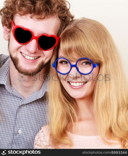 Happy young man in heart shaped glasses and woman. Smiling friends couple in studio.. Happy couple man and woman in glasses.