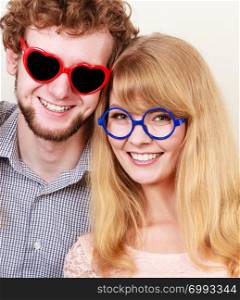 Happy young man in heart shaped glasses and woman. Smiling friends couple in studio.. Happy couple man and woman in glasses.