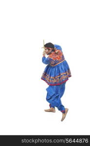 Happy young man in kedia and dhoti performing Dandiya Raas over white background