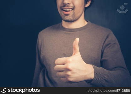 Happy young man is giving one thumb up