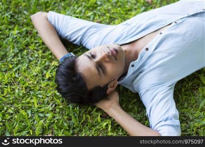Happy young man lying on the grass relaxing