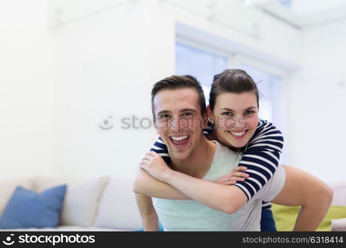 happy young man piggybacking his girlfriend at home