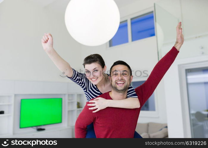 happy young man piggybacking his girlfriend at home