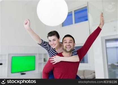 happy young man piggybacking his girlfriend at home