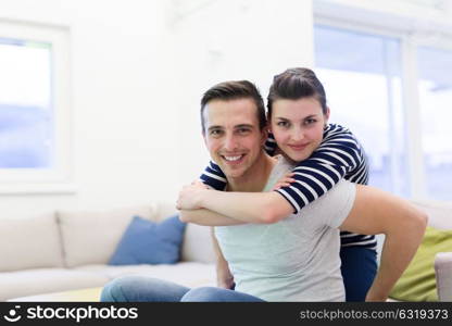 happy young man piggybacking his girlfriend at home