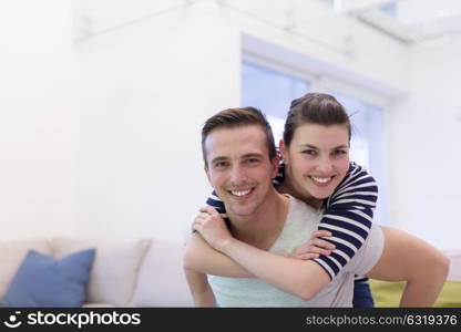 happy young man piggybacking his girlfriend at home