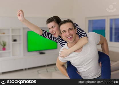 happy young man piggybacking his girlfriend at home