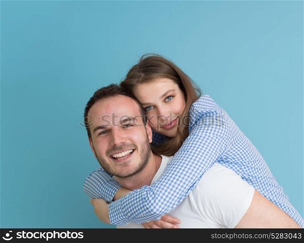 happy young man piggybacking his girlfriend isolated on blue background