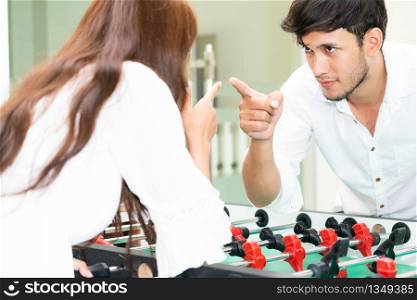 Happy young man playing foosball table soccer with girlfriend. Couple recreation and lifestyle.. Happy couple playing foosball table.