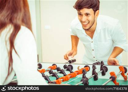 Happy young man playing foosball table soccer with girlfriend. Couple recreation and lifestyle.. Happy couple playing foosball table.