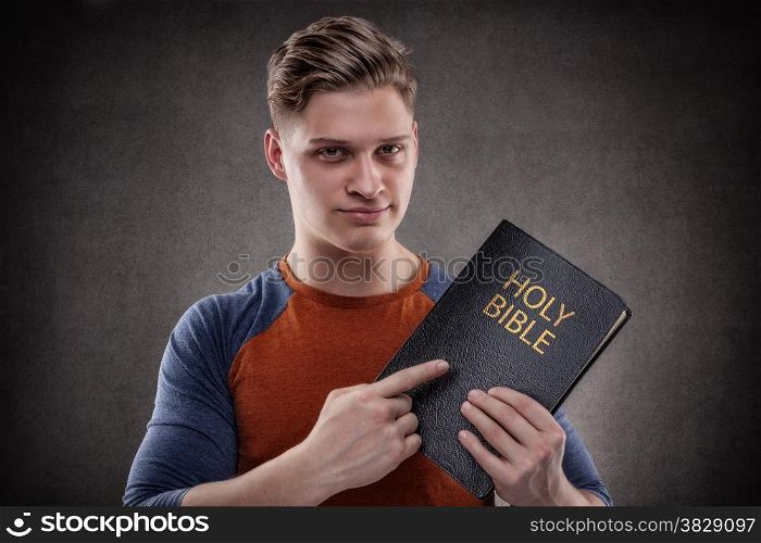 Happy young man pointing his Holy Bible with leather covers