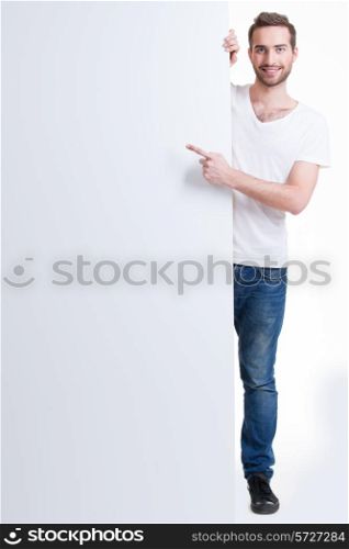 Happy young man points finger on a blank banner - isolated on white.