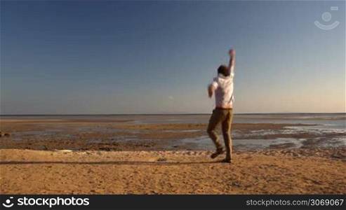 Happy young man running far away on the beach