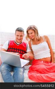 Happy young man showing his pregnant wife something in laptop&#xA;