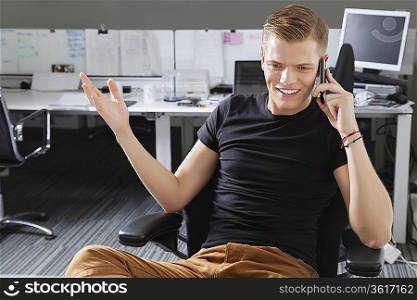 Happy young man using cell phone at office