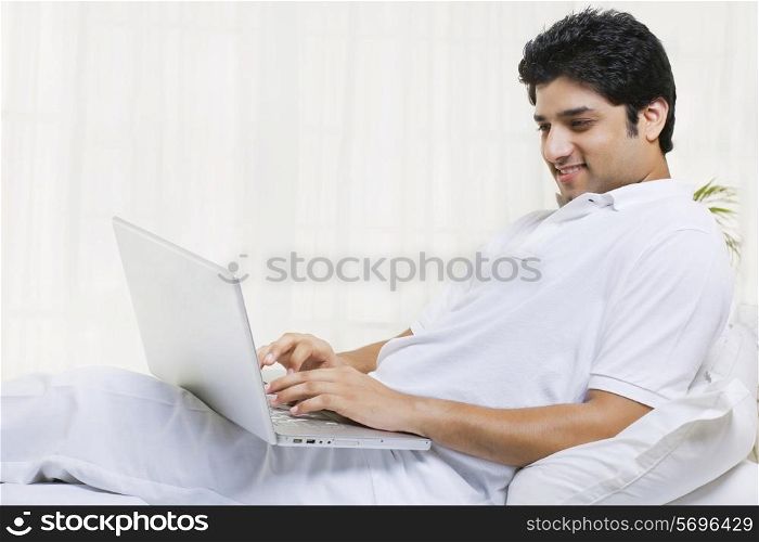Happy young man using laptop at home