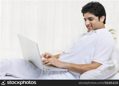 Happy young man using laptop at home