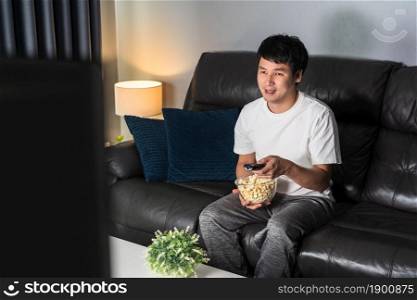 happy young man watching TV on sofa at night