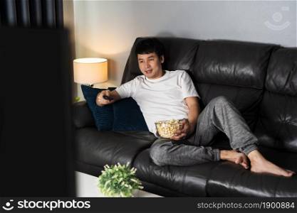 happy young man watching TV on sofa at night