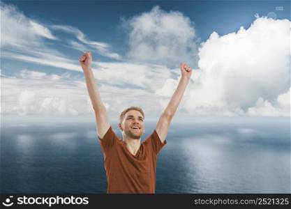 Happy young man with both arms up over a blue sky. Happy young man