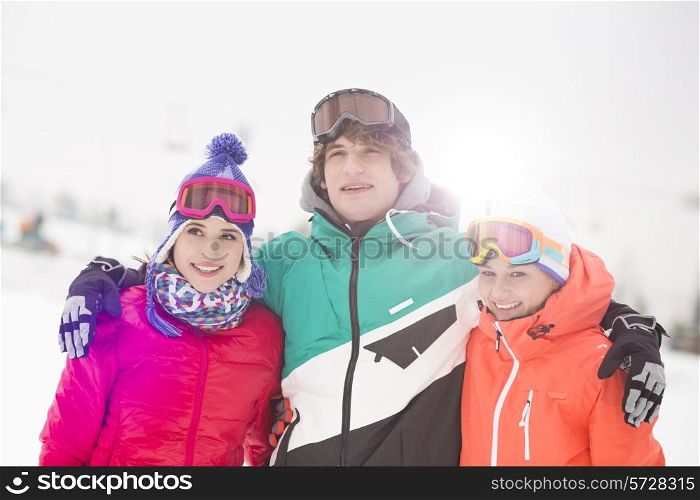 Happy young man with female friends standing arm around in snow