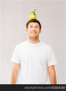 happy young man with green apple on his head