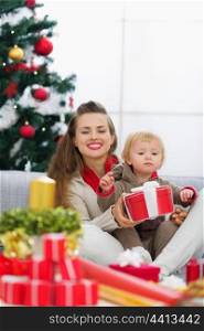 Happy young mother and baby looking on table with Christmas gifts