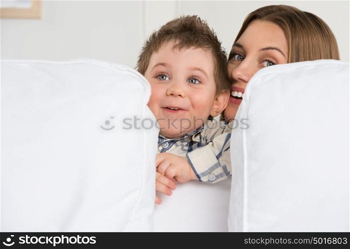 Happy young mother and her cute son playing at home