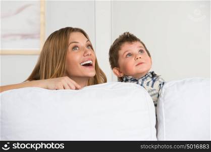 Happy young mother and her cute son playing at home and dreaming