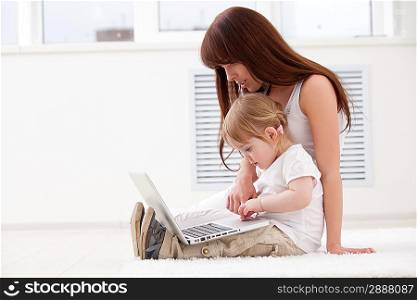 Happy young mother and her daughter using a laptop