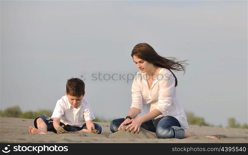 happy young mother and son relaxing and play ind sand games on beach at summer season