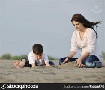 happy young mother and son relaxing and play ind sand games on beach at summer season