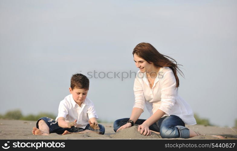 happy young mother and son relaxing and play ind sand games on beach at summer season