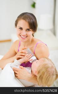 Happy young mother feeding baby