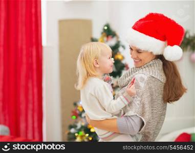 Happy young mother holding baby near Christmas tree